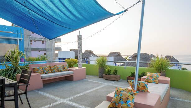 A rooftop terrace with seating areas, potted plants, and a view of the sea.