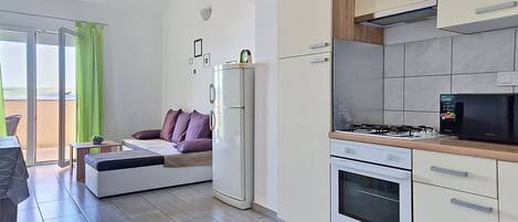 A modern kitchen with a built-in oven, a refrigerator, and a microwave.
