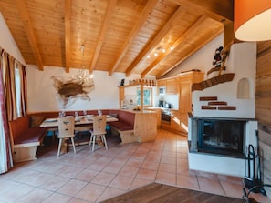 Un intérieur chaleureux en bois, comprenant un coin repas, une cuisine et une cheminée.