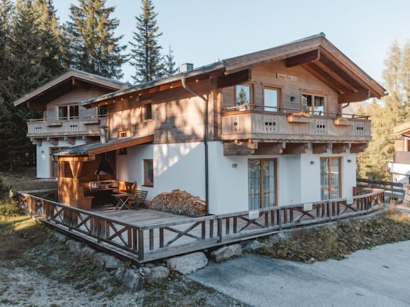 Un chalet en bois à deux étages, doté d’un balcon, d’une terrasse et de fondations en pierre.