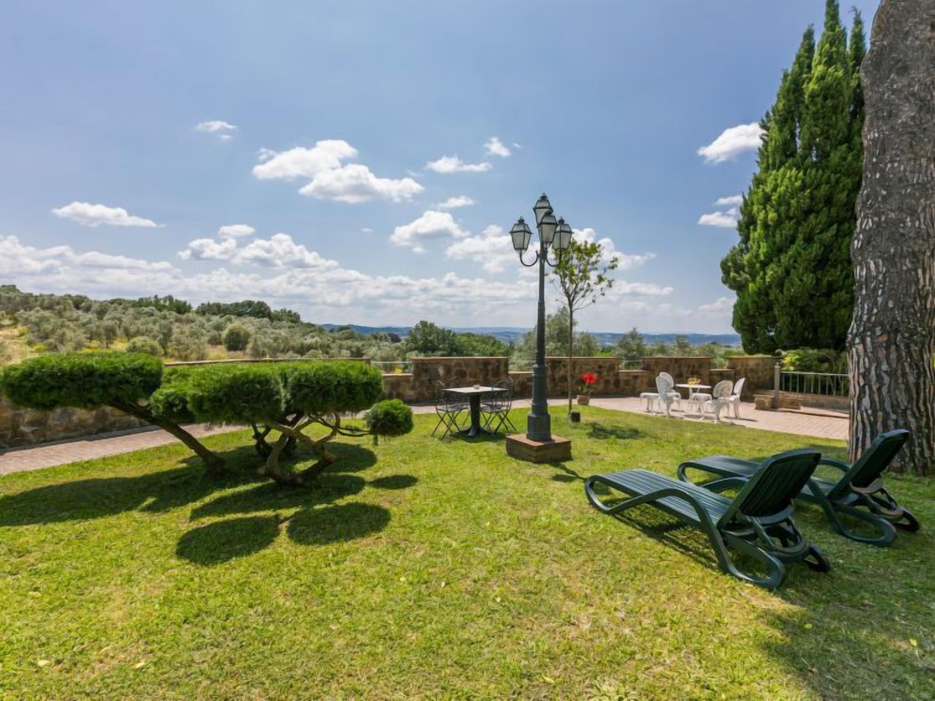 Eine gepflegte Außenpatio mit Blick auf die Landschaft, mit ordentlich geschnittenen Hecken, einem Laternenpfosten und Sitzgelegenheiten im Freien.
