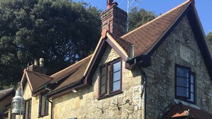 A stone building with a traditional architectural style, featuring a stone facade, multiple windows, and a sloped roof. - Little Treasure in Heart of Old Village Shanklin + Ferry Discount  (Shanklin)