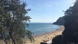 A beach with a clear view of the sea, a rocky cliff, and a few people and umbrellas. - Little Treasure in Heart of Old Village Shanklin + Ferry Discount  (Shanklin)