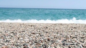 A pebbled beach with waves crashing onto the shore.