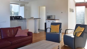 Un salon moderne avec un canapé en cuir rouge, un fauteuil bleu et une table basse en bois.