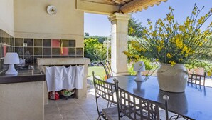 Un patio al aire libre con una mesa y sillas, un revoque de azulejos y una maceta con flores amarillas.