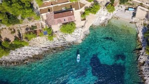 An aerial view of a coastal property with a house, clear turquoise waters, and a boat. - Villa Golubinka by Interhome (Hvar/Zastražišće)
