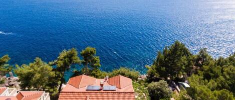 A coastal residential area with houses featuring red-tiled roofs and a view of the sea.