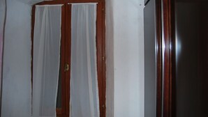 Una habitación con puerta de madera y cortina blanca.