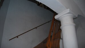 Un pilar blanco con barandilla de madera y escaleras de metal.