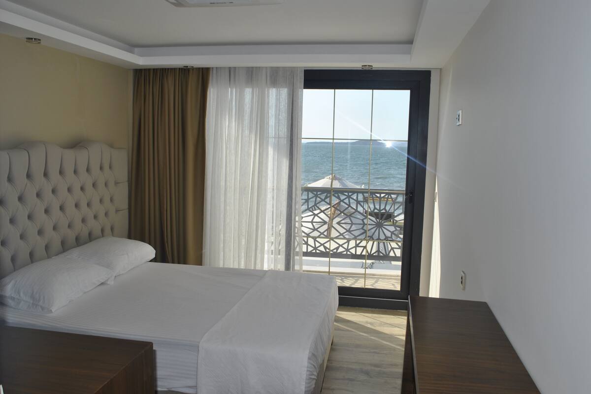 Habitación de hotel con una cama grande, vistas al mar desde un balcón y un diseño moderno.