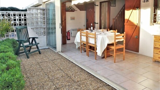 A patio with a table set for dining, a chair, and a fire extinguisher. - L'Hacienda by Interhome (Gruissan)