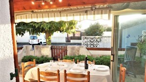 An outdoor dining area with a round table set for four, surrounded by wooden chairs. - L'Hacienda by Interhome (Gruissan)