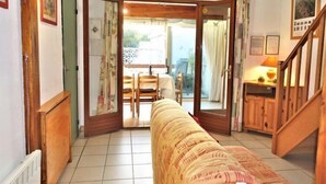 A cozy living room with a sofa, wooden furniture, a dining area with chairs and a table, and a staircase leading upstairs. - L'Hacienda by Interhome (Gruissan)