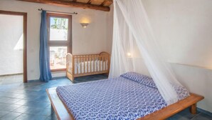 Quarto com cama de madeira, dossel e vista para uma varanda.