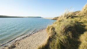 Una spiaggia con acqua cristallina, una riva sabbiosa e dune erbose.