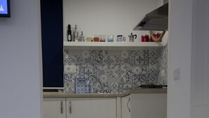 A kitchen with white cabinets, a tiled backsplash, and a countertop with various items. - The Holy Mary inside (Tropea)