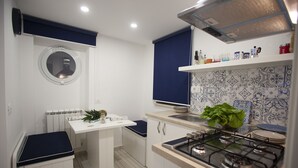 A compact kitchen with a gas stove, white cabinets, a small island, and a blue backsplash. - The Holy Mary inside (Tropea)