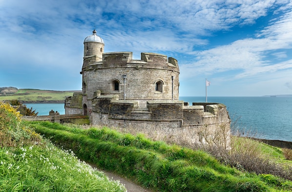 A historic stone tower with a dome, overlooking a coastal area with a clear sky.