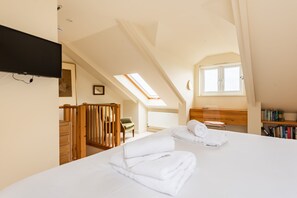 A bedroom with a bed, a desk, a chair, a bookshelf, and a television. - Captains Cottage - Four Bedroom Cottage, Sleeps 7 (St Mawes)