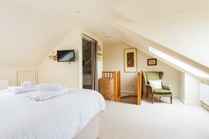 A bedroom with a bed, a TV mounted on the wall, a chair, and a small desk. - Captains Cottage - Four Bedroom Cottage, Sleeps 7 (St Mawes)