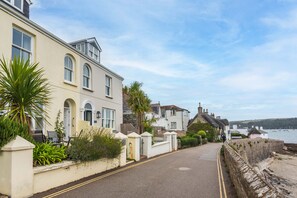 A coastal street with buildings, a stone wall, and a view of the sea. - Captains Cottage - Four Bedroom Cottage, Sleeps 7 (St Mawes)