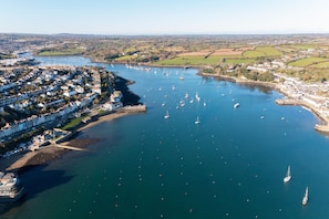 An aerial view of a coastal town with a marina, boats, and residential buildings.