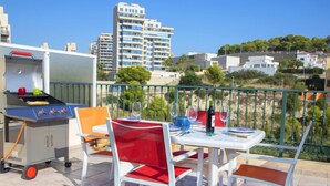 Ein Balkon mit Grill, Esstisch und Stühlen.