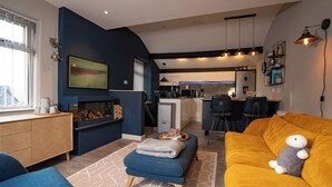 Un salon moderne avec un canapé, un pouf et une cheminée.