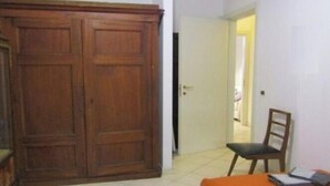 Een kamer met een grote houten garderobe, een stoel en een bed met een oranje sprei.
