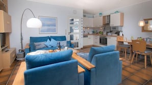 Una sala de estar moderna con un sofá azul, una mesa de centro de madera y un ventanal grande.