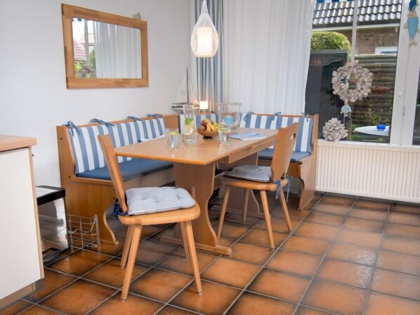 A dining area with a wooden table, striped blue and white cushioned benches, and a hanging pendant light. - Achtern Diek 24 by Interhome (Norddeich)