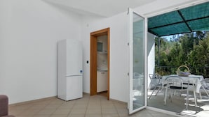 A modern apartment with a white refrigerator, a wooden door leading to a kitchen, and a balcony with a table and chairs. - Apartment Rubin by Interhome (Hvar/Pokrivenik)