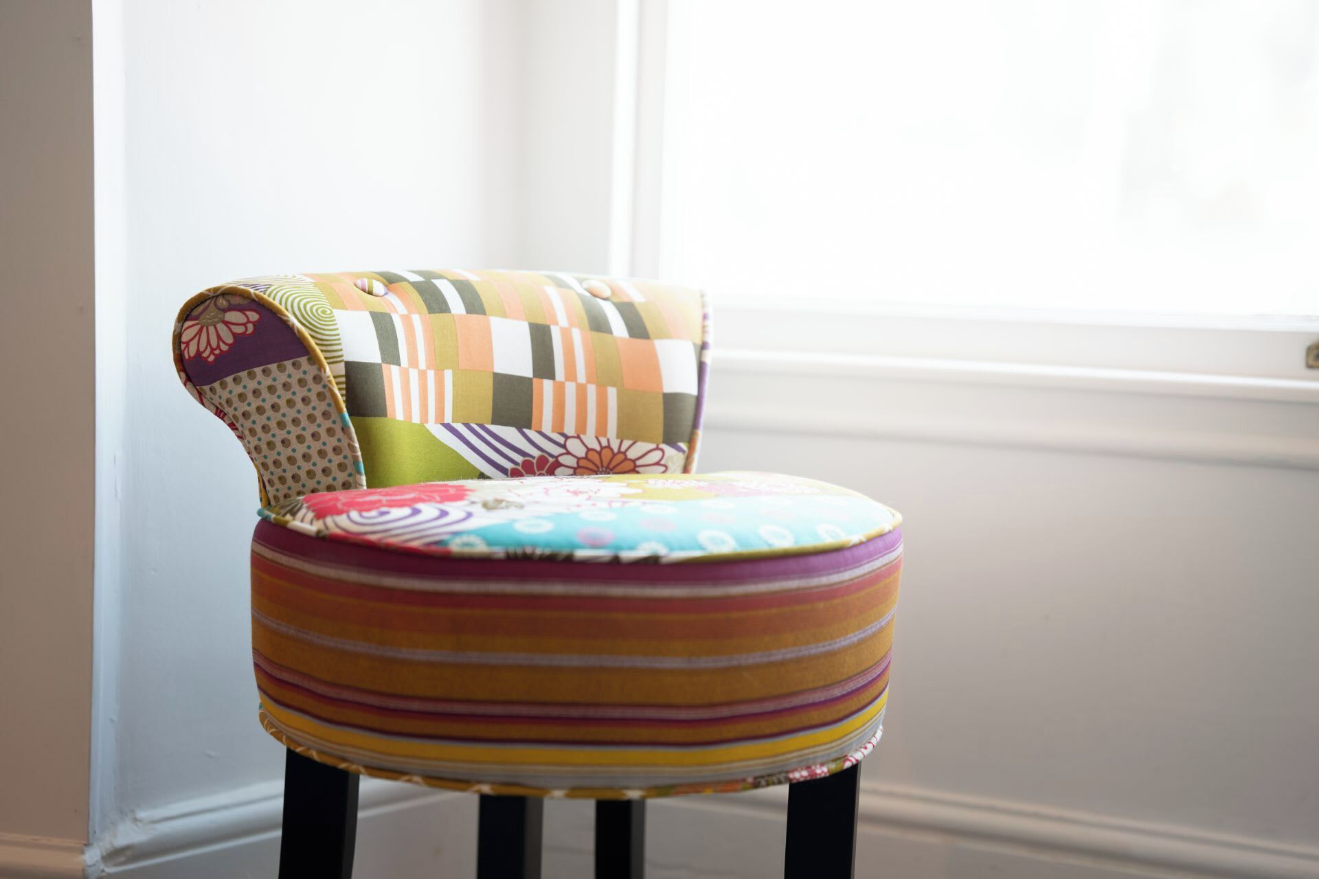 A chair with a colorful, patterned cushion and a fabric backrest.