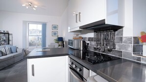Une cuisine moderne équipée d’un four encastré, d’une plaque de cuisson et d’un four à micro-ondes. Une fenêtre offre une vue sur l’extérieur.