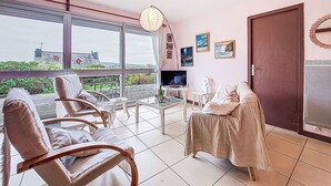 Un espace de vie spacieux avec une grande fenêtre, un téléviseur à écran plat et un coin salon confortable.