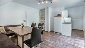 Ein moderner, kompakter Wohnraum mit Essbereich, Küchenzeile und einer Couch.