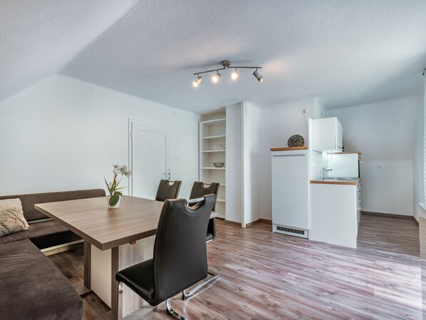 A modern, compact living space with a dining area, kitchenette, and a sofa. - Apartment Ogris by Interhome (Velden am Wörthersee)