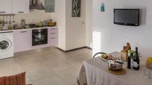 A modern kitchen with a washing machine, oven, and dining area with a table set for a meal. - Cava Larica by Interhome (Scicli)