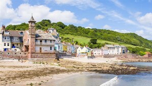 A coastal town with a prominent clock tower, colorful buildings, and a sandy beach. - Emelle - Three Bedroom Cottage, Sleeps 7 (Kingsand)