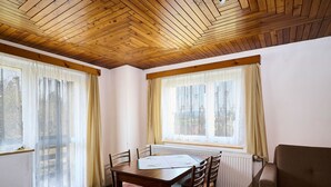 Un espace repas avec une table en bois, des chaises et une vue dégagée grâce à de grandes fenêtres.