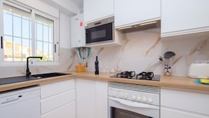 Una cocina moderna con armarios blancos, un microondas, una estufa y un lavavajillas.
