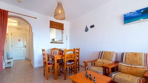 Una sala de estar con una mesa de comedor de madera, sillas, un sofá y una lámpara colgante.
