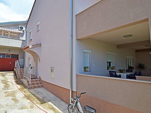 A two-story building with a covered outdoor area, a staircase, and a parked motorcycle.