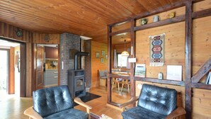 A cozy cabin interior with a fireplace, leather chairs, wooden walls, and a dining area. - Vacation home Clobes by Interhome (Wabern)