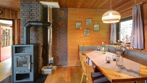 A cozy cabin interior with a wood-burning stove, a dining table with chairs, and a bench. - Vacation home Clobes by Interhome (Wabern)