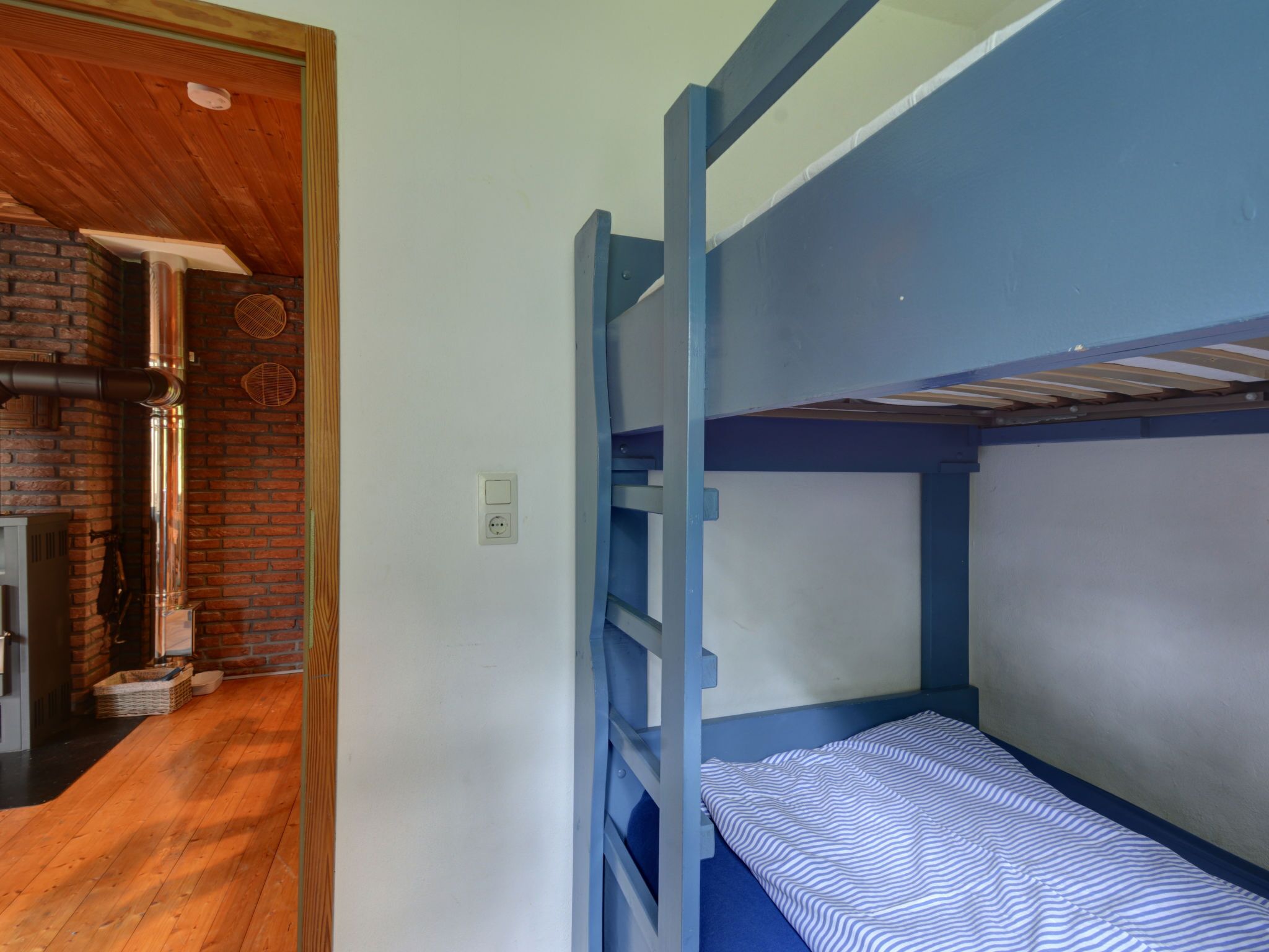 Ein Mehrbettzimmer mit Backsteinofen und Holzboden.