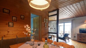 A wooden interior with a dining table, chairs, a bottle of wine, and a vase with flowers. - Vacation home Clobes by Interhome (Wabern)