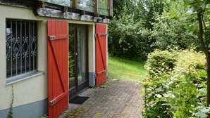 A building with a red door and window shutters, a brick pathway, and lush greenery. - Vacation home Clobes by Interhome (Wabern)