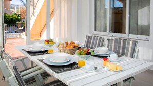 Et morgenbord dækket med tallerkener, skåle og en kurv med brød og frugt.